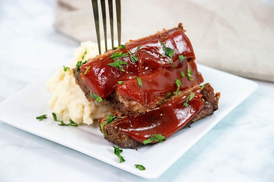 Finished meatloaf with sauce and fork on plate