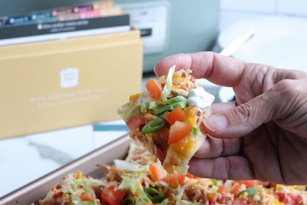 Slow Cooker Chicken Nachos in hand with Recipe box in background