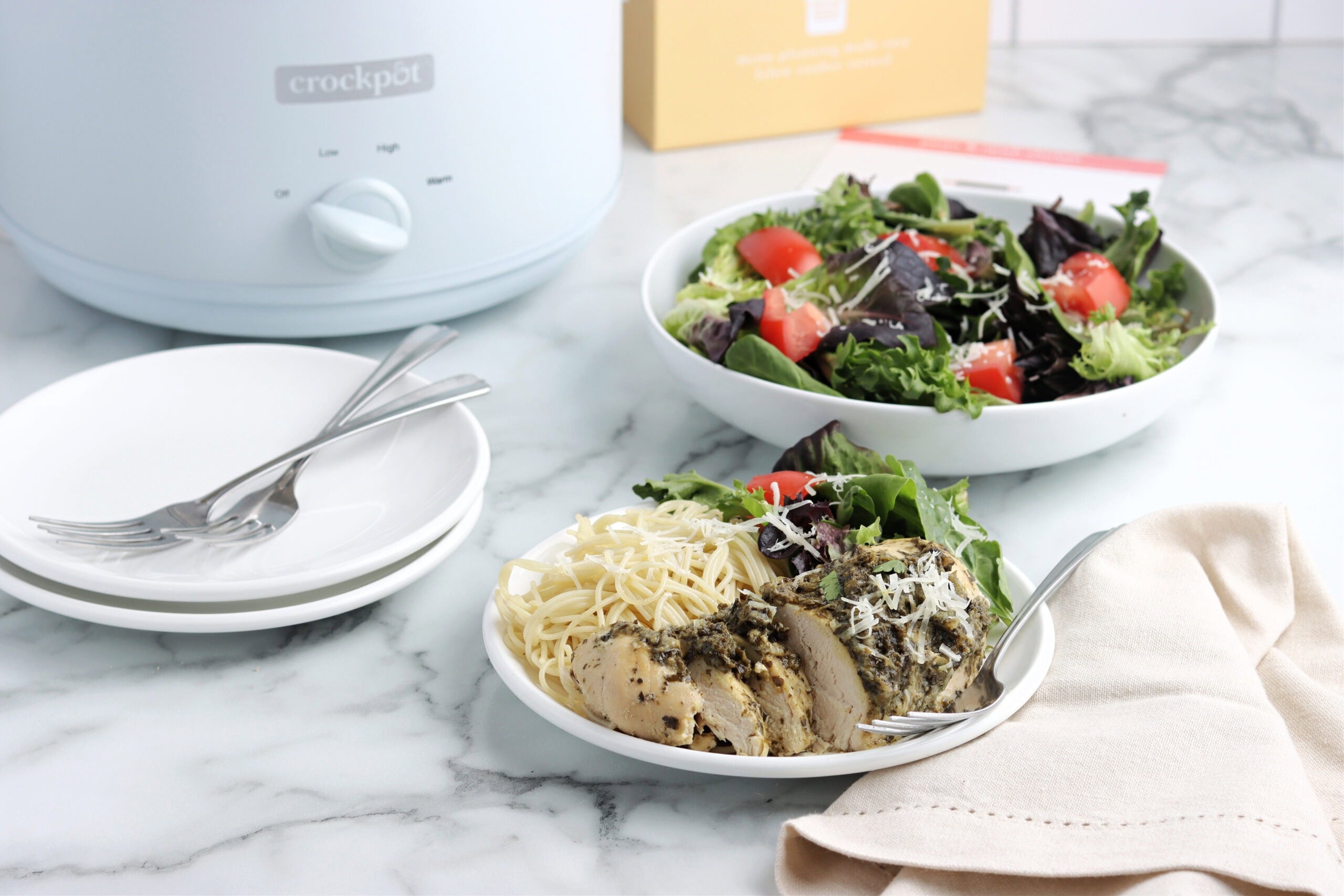 Pesto & Ranch chicken on plate with salad and pasta with white crockpot in background