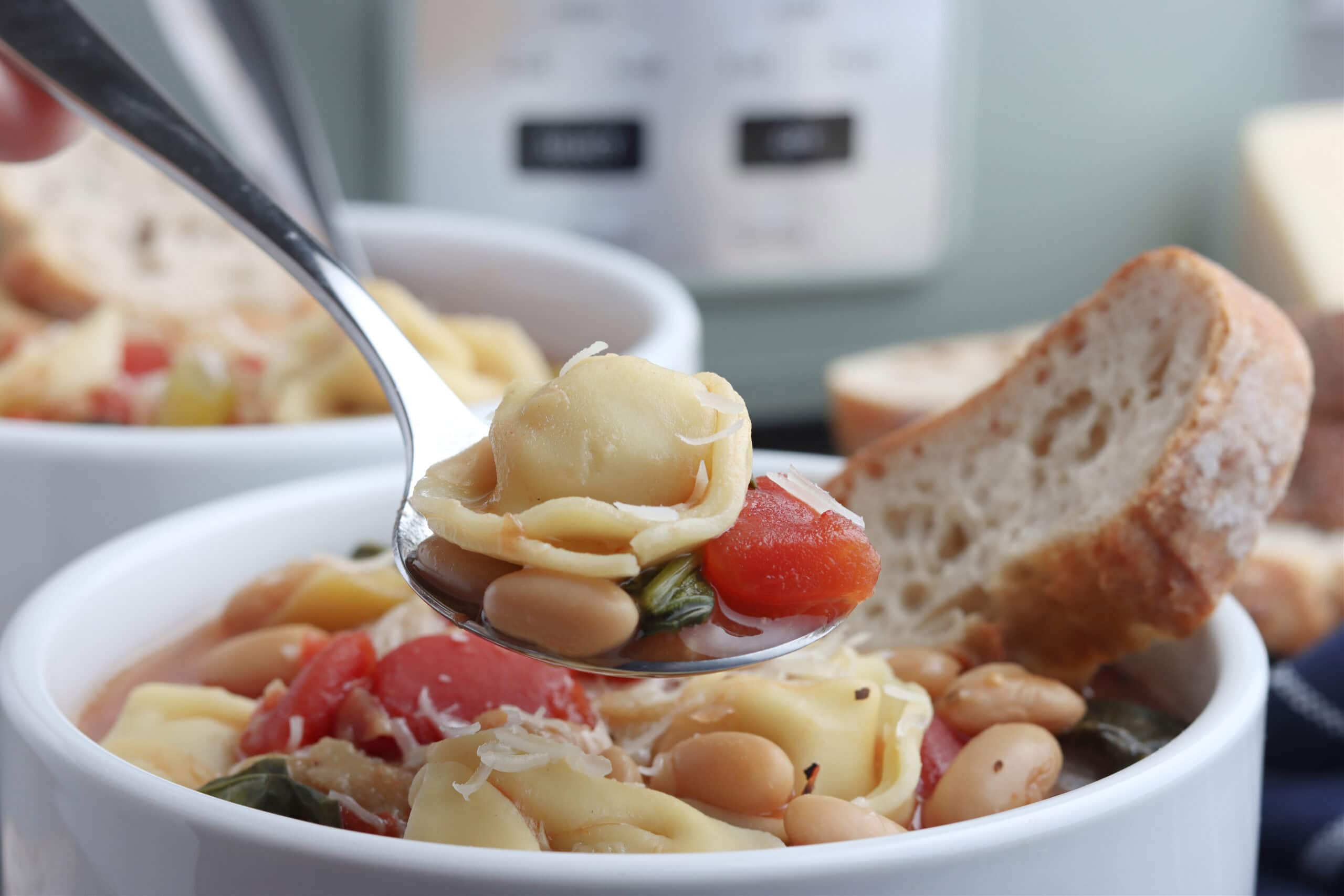 up close picture of tortellini from bowl of soup with bread 