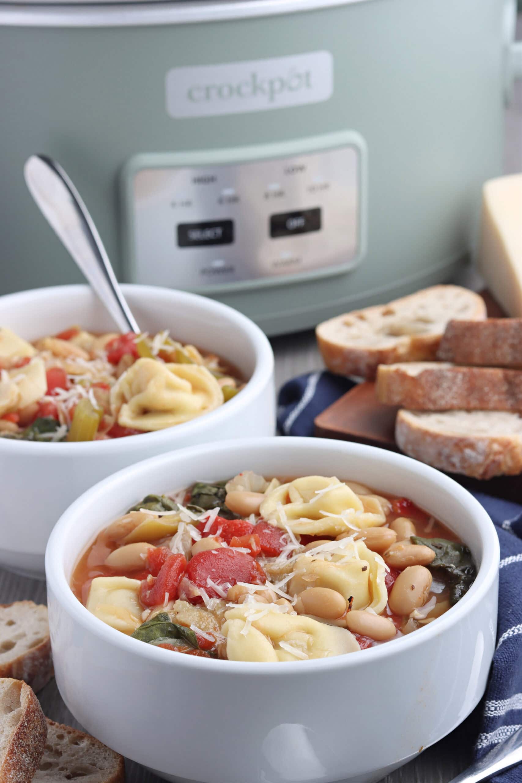 tortellini soup in bowls with bread and a crockpot in the background