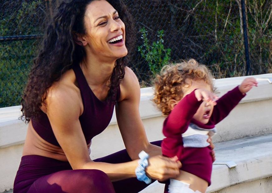 woman wearing workout clothes holding toddler