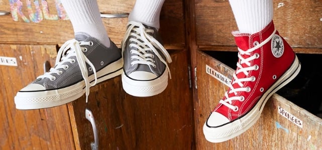legs dangling wearing gray and red Converse shoes