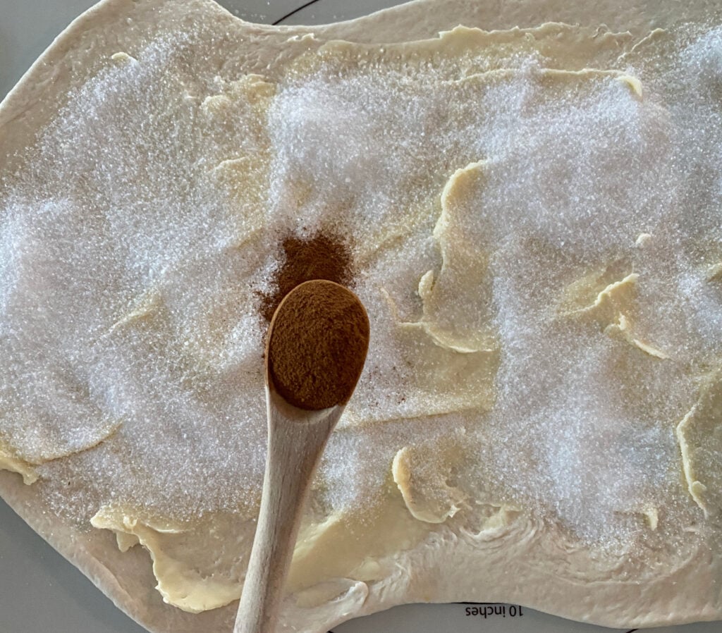 cinnamon sugar and butter spread on top of rolled out bread dough