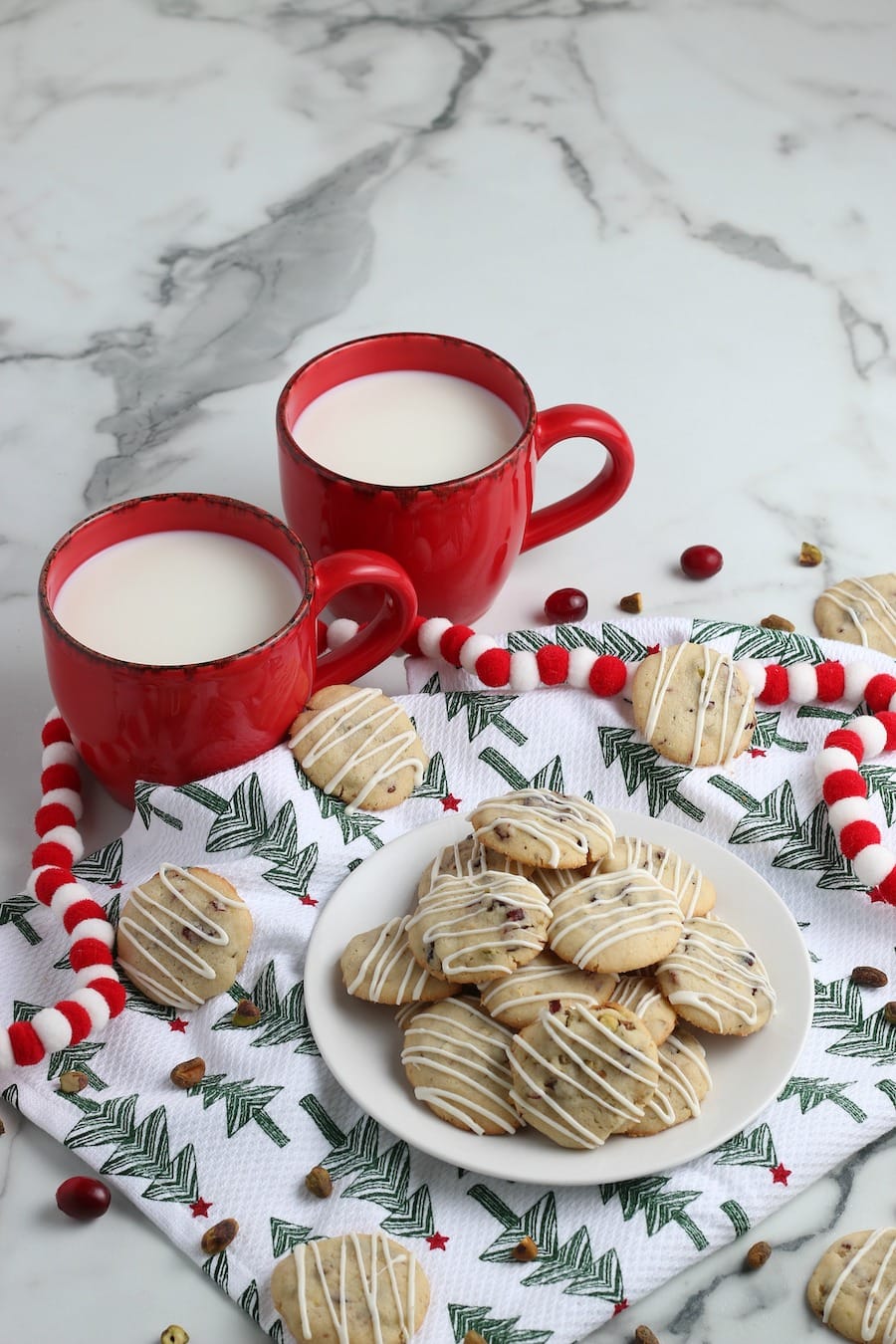 cranberry pistachio cookies on platter with milk