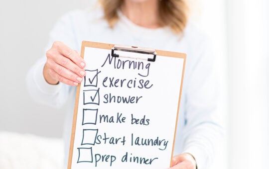 Laurie holding sign with morning checklist of things to do