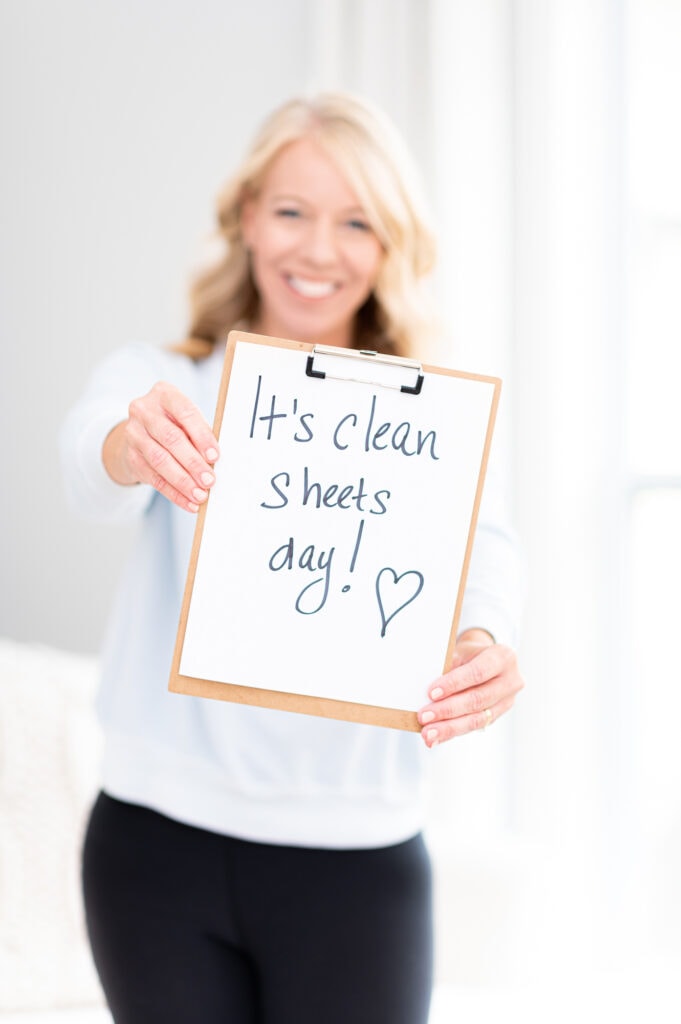 Laurie holding a sign that says, "it's clean sheets day"