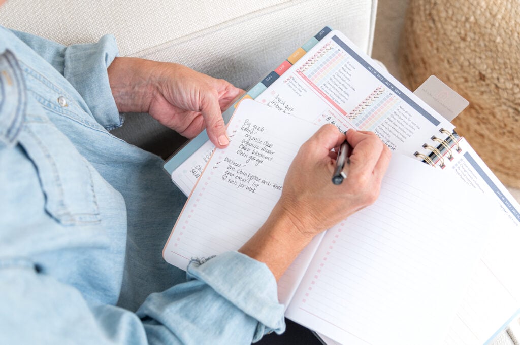 Laurie writing in blank journal with planner