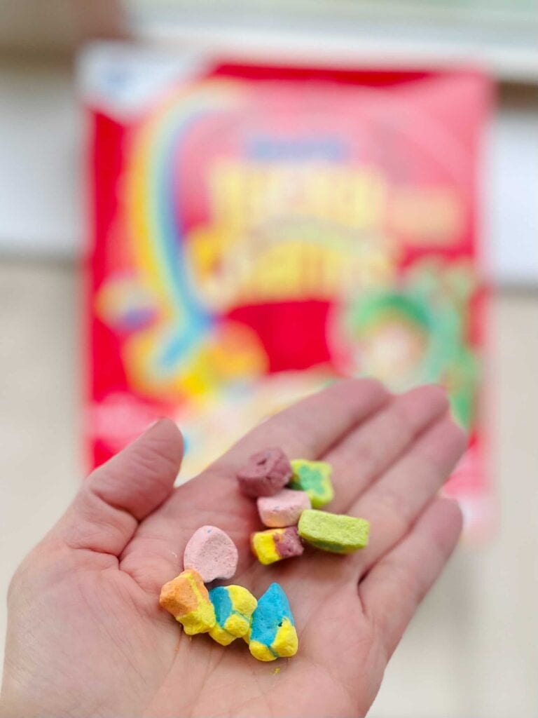 lucky charms marshmallows in hand with cereal box in the background