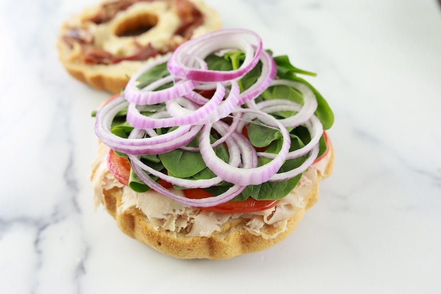 Adding veggies to party sandwiches