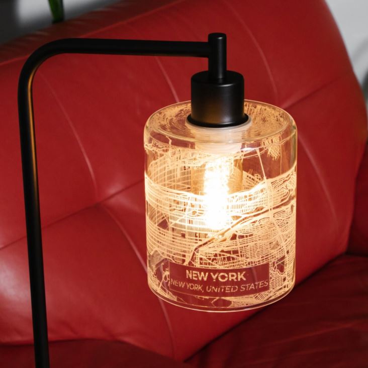 lamp with map of new york city imprinted on it with red couch in background