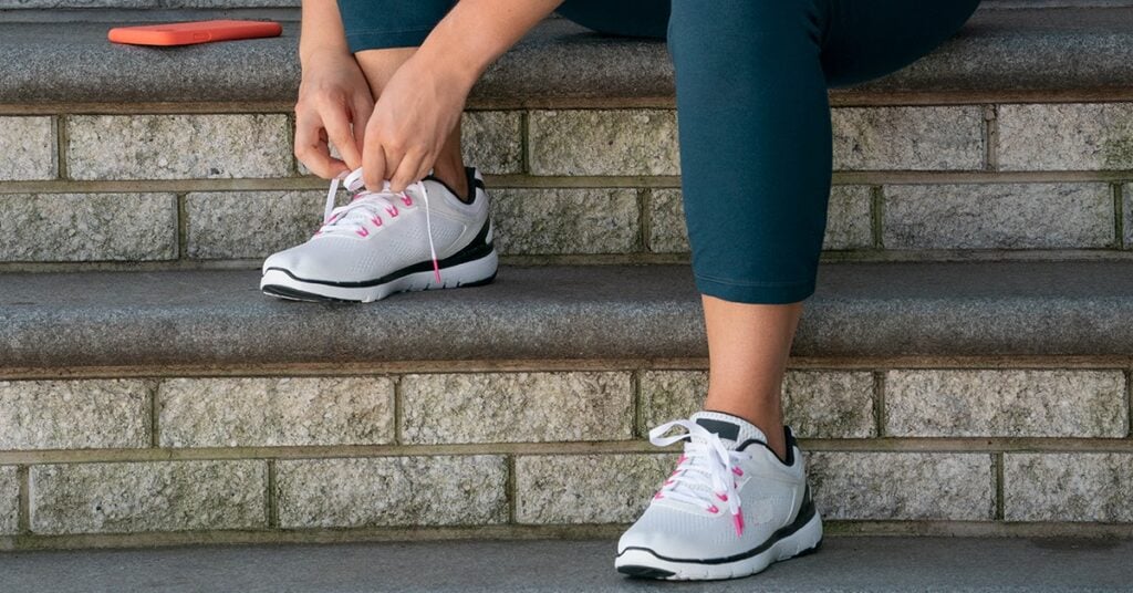 weight-watchers person tying gym shoes on steps