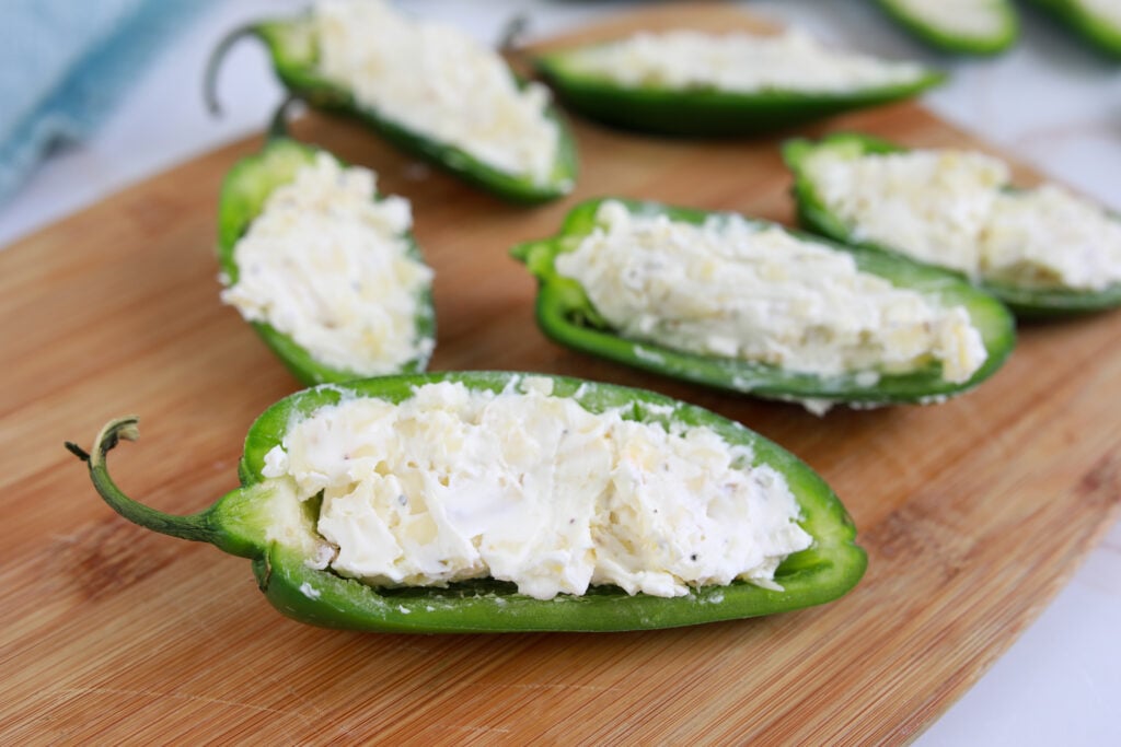 jalapeno poppers stuffed before cooking on wooden board
