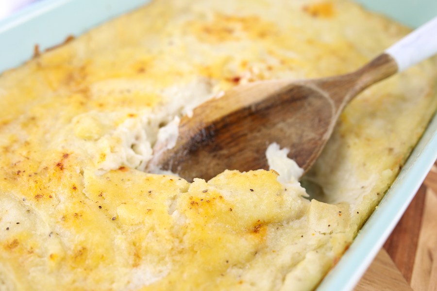 scooping out mashed potato casserole with wooden spoon