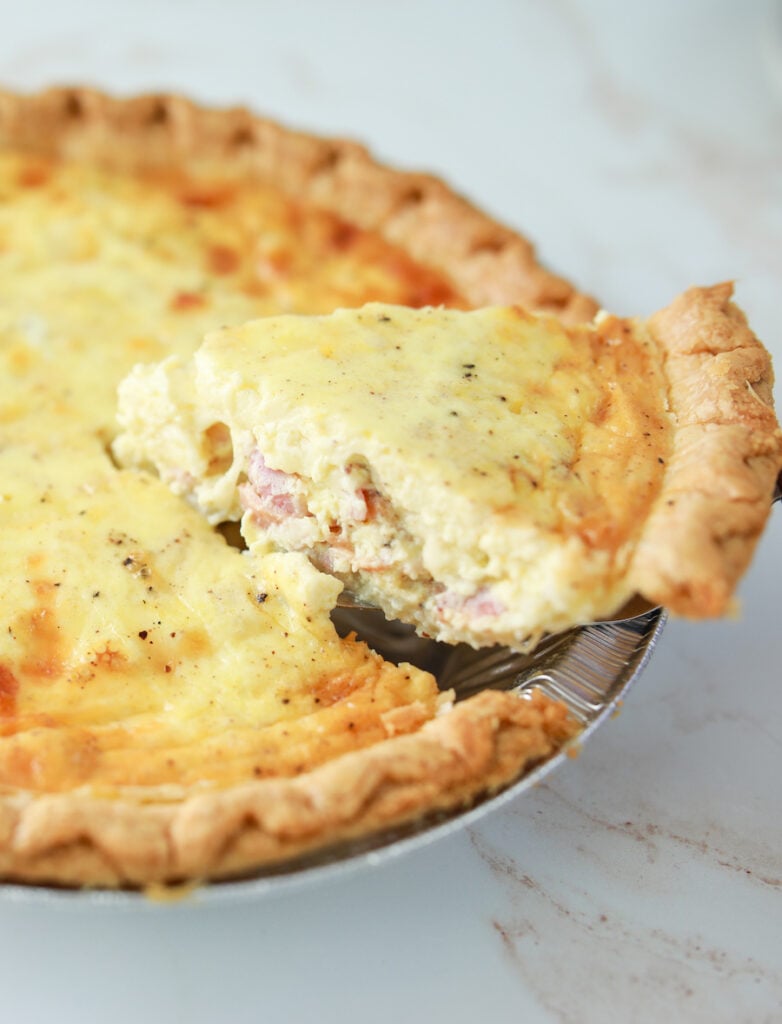 quiche finished baking with a piece sliced coming out the pan