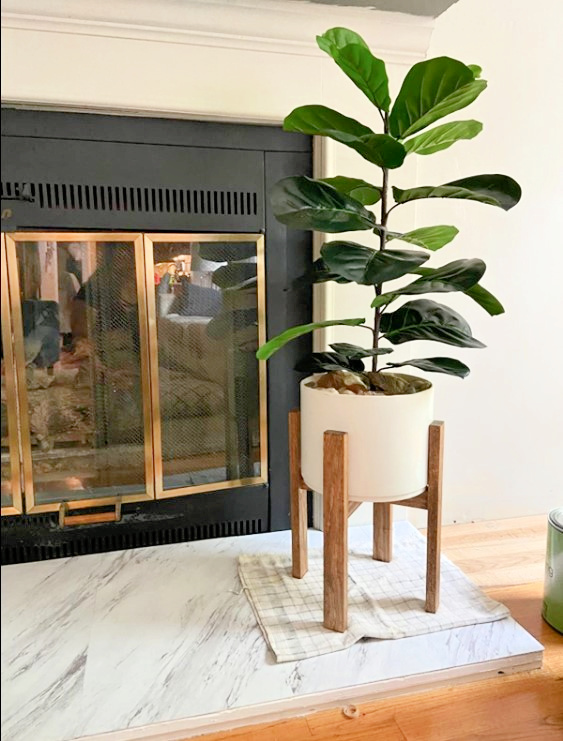fake plant in living room next to fireplace