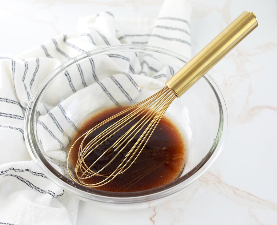 dressing in a clear glass bowl with whisk in bowl