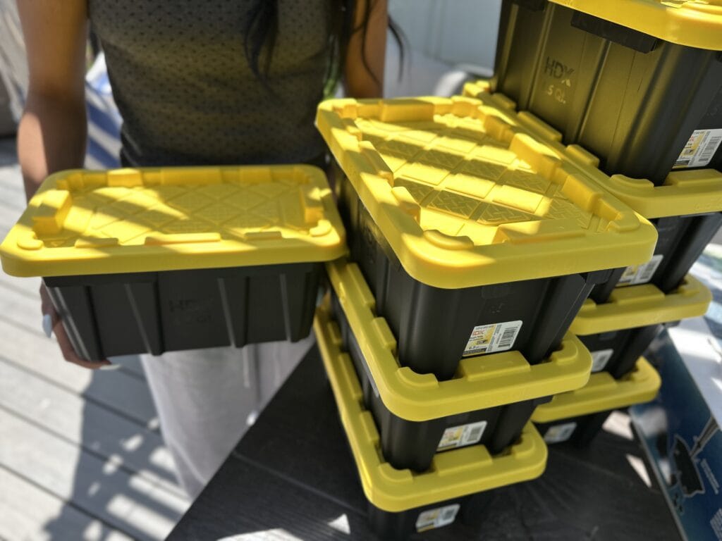 person holding onto green and yellow storage tote