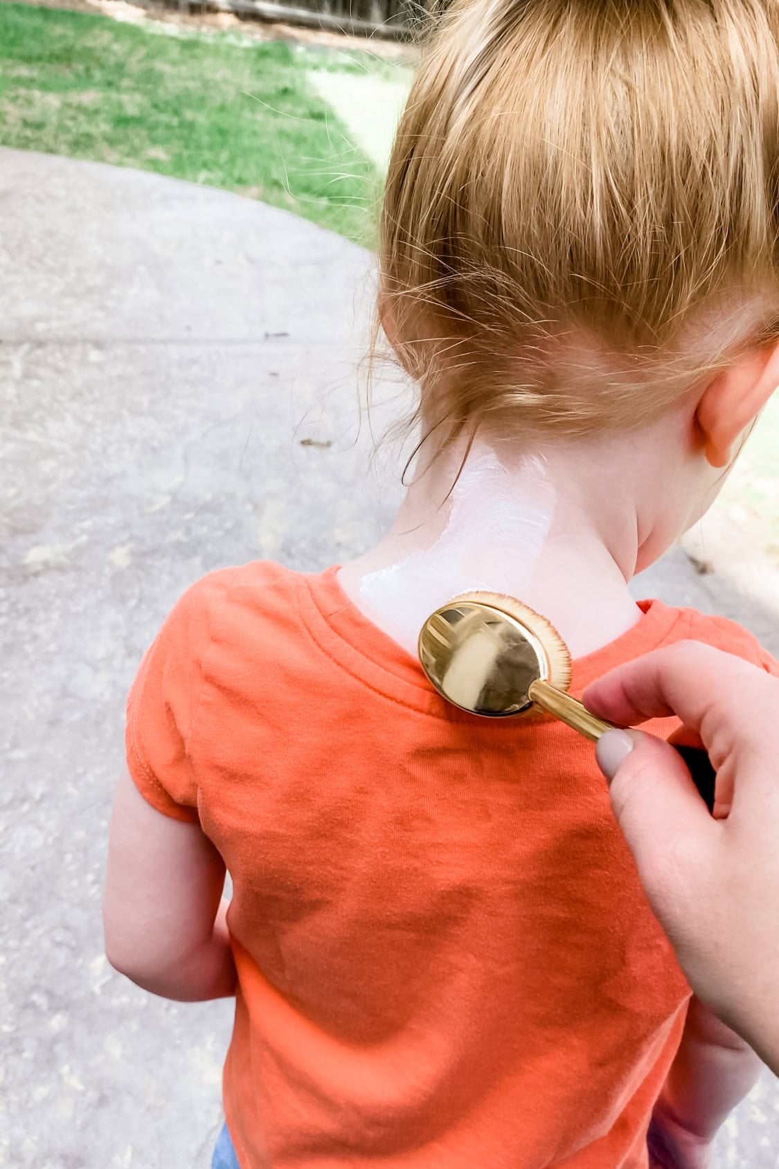applying sunscreen to childs neck using makeup brush