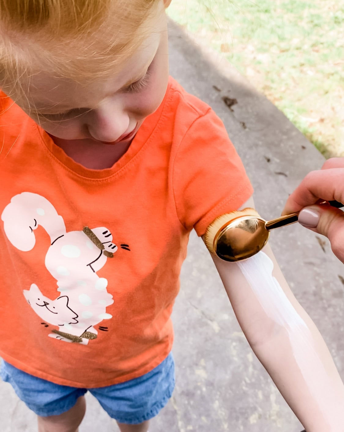 applying sunscreen to child's arm using makeup brush