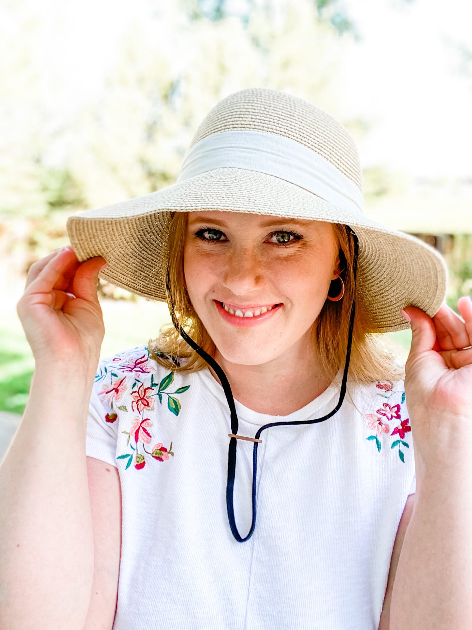 woman with hands on side of sun hat 