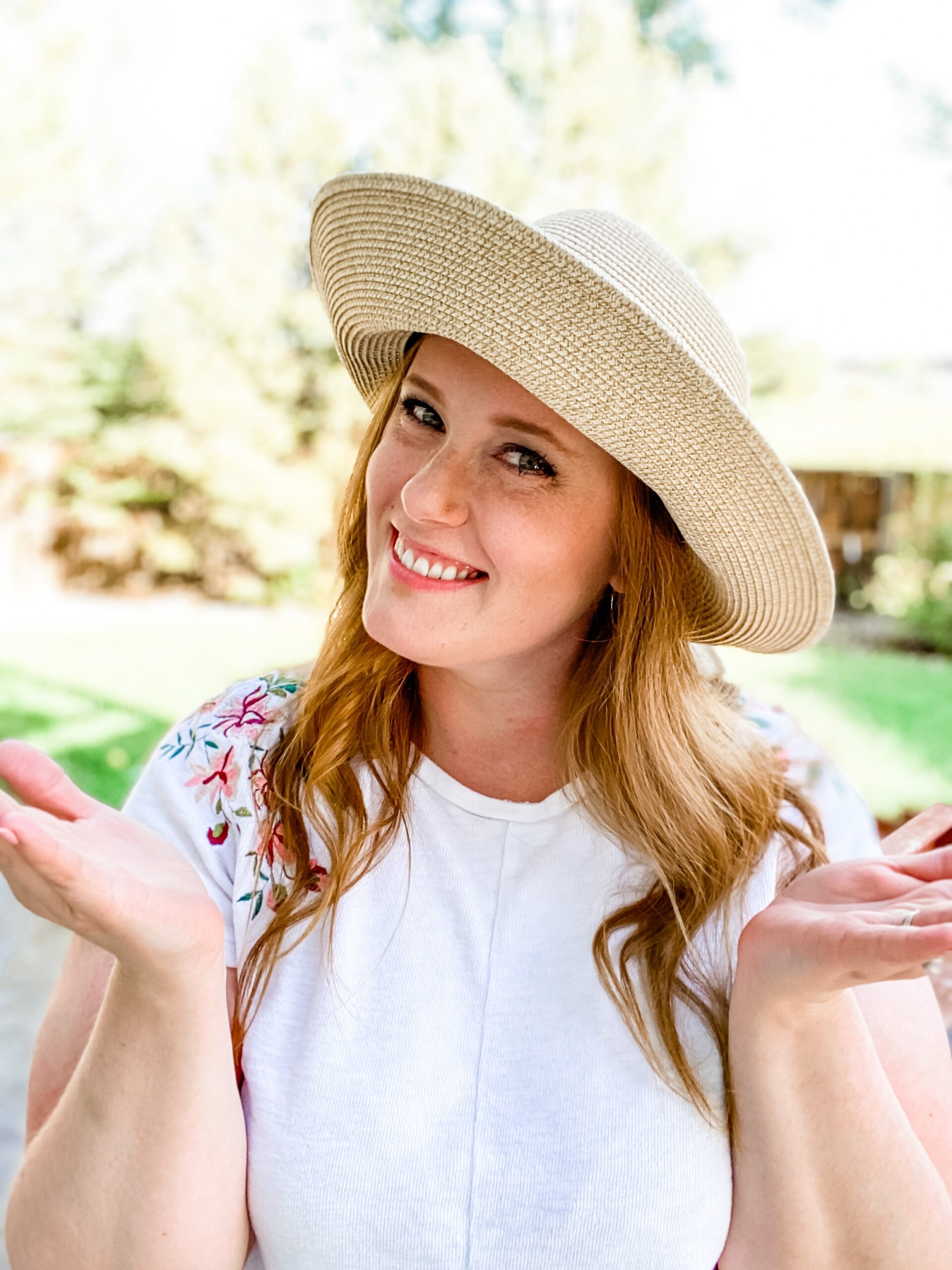 beige sun hat being worn by woman with red hair in white shirt 