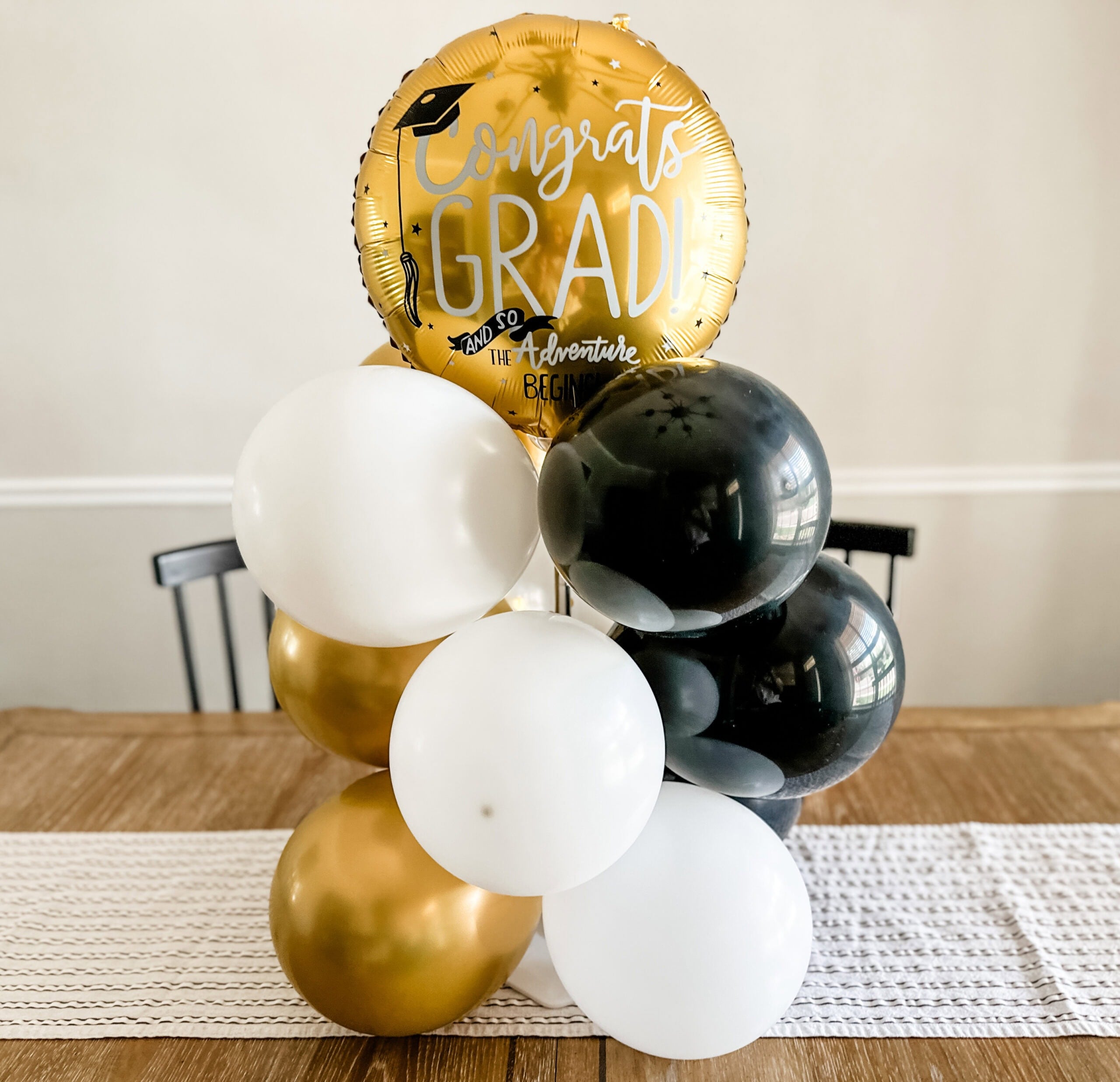 diy balloon bouquet with white, gold, and black balloons sitting on a table.
