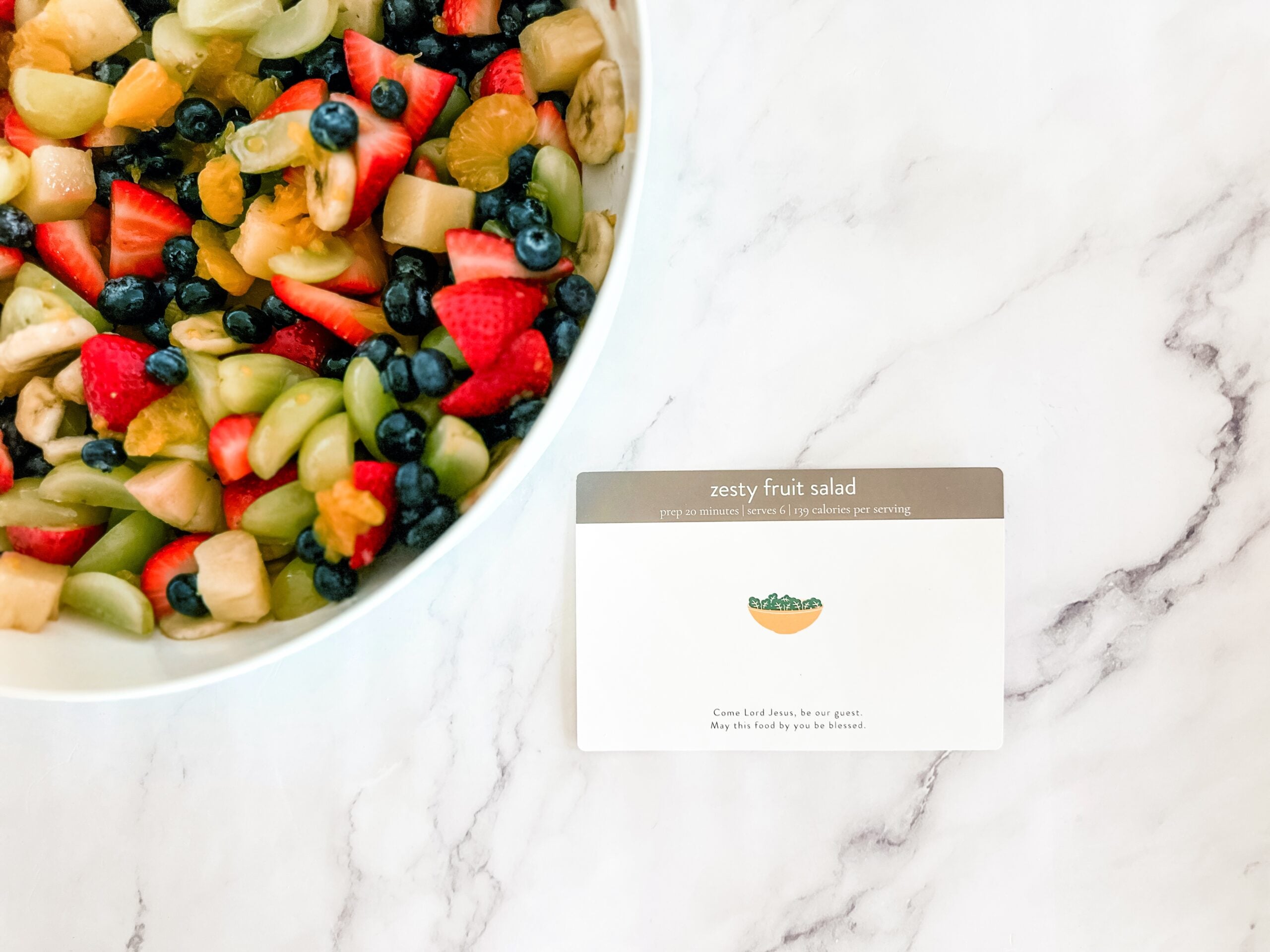 fruit salad recipe card next to bowl of fruit salad 
