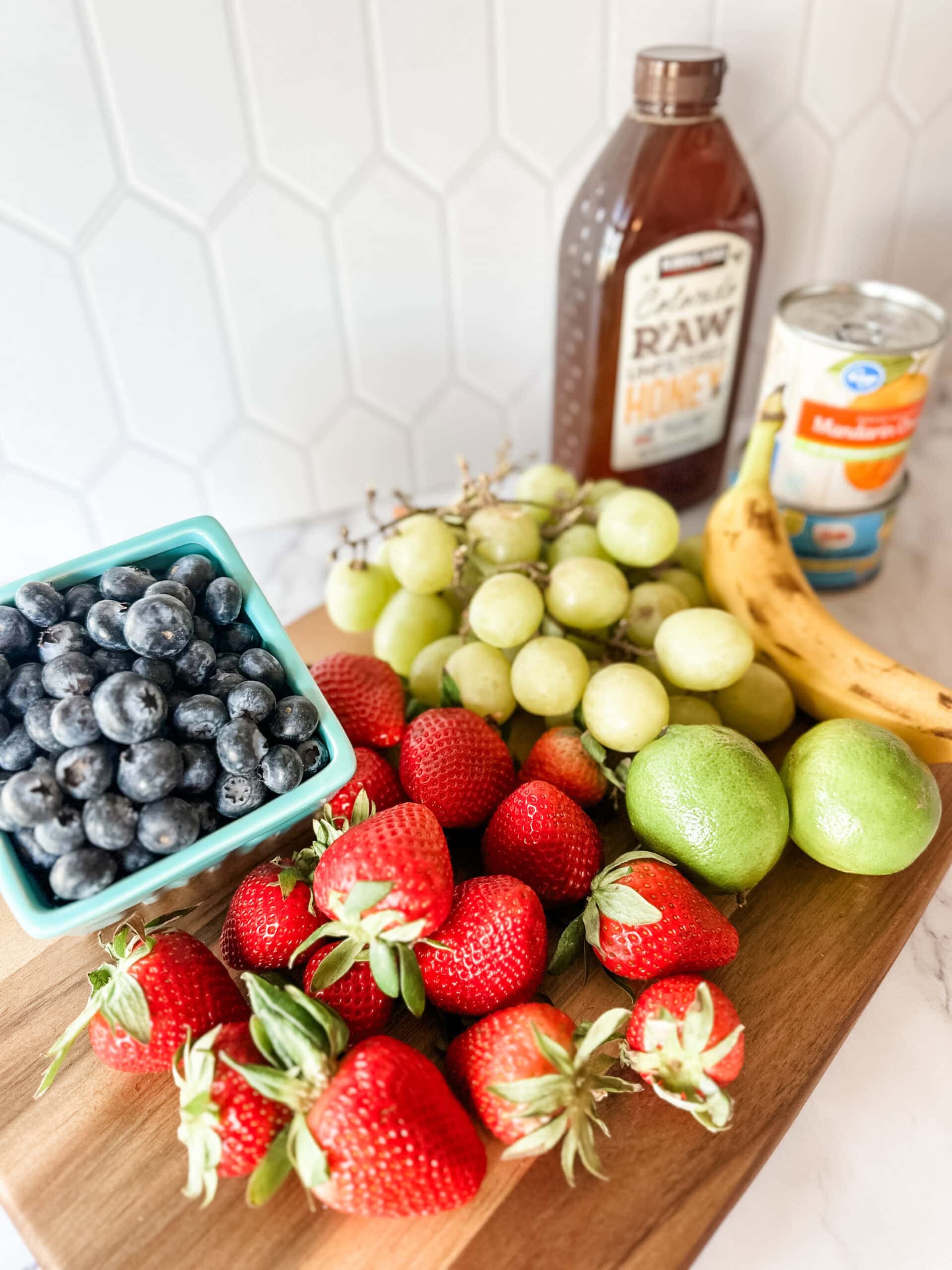 ingredients to make fruit salad with dressing on cutting board