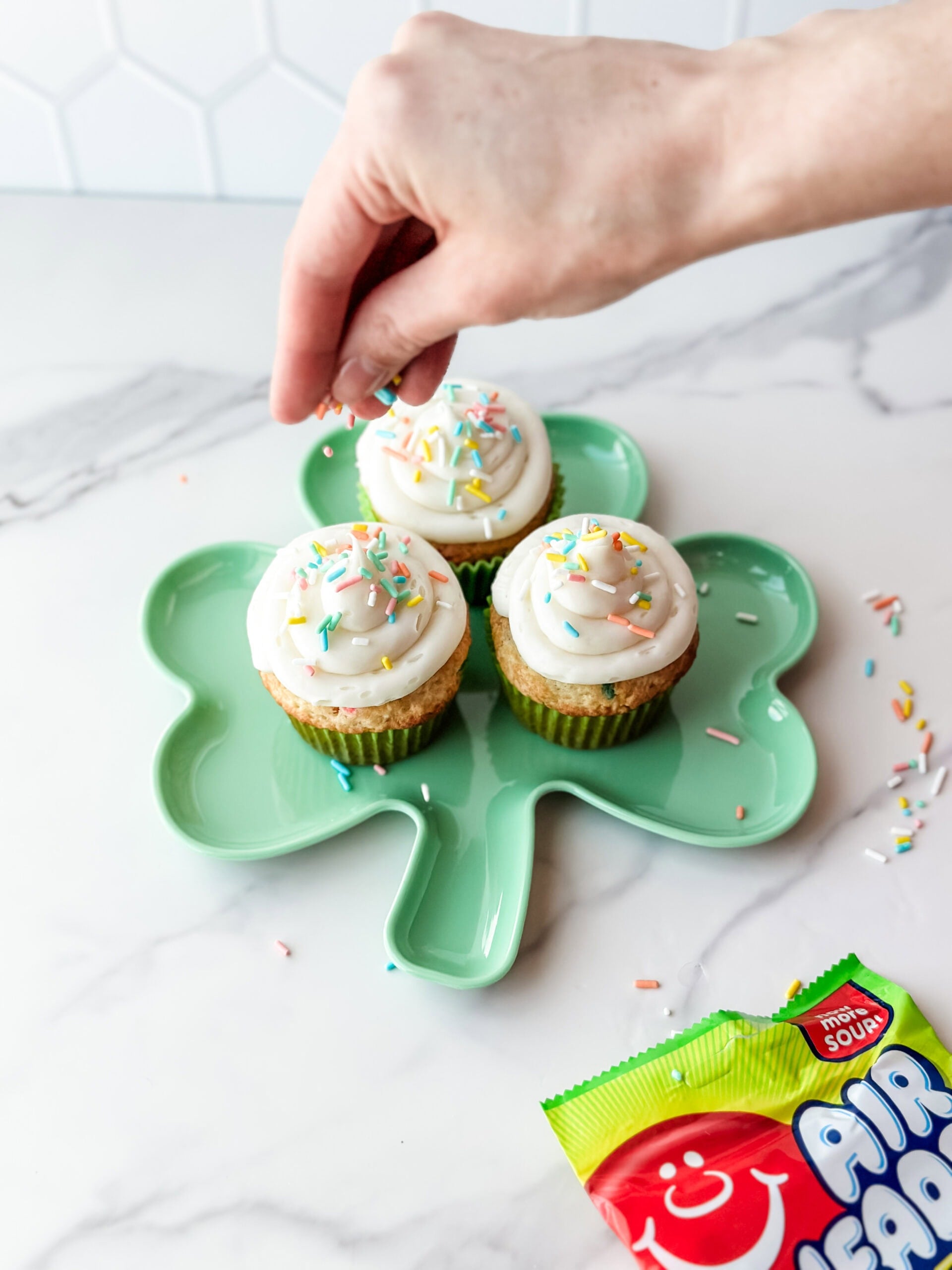 adding sprinkles to cupcake