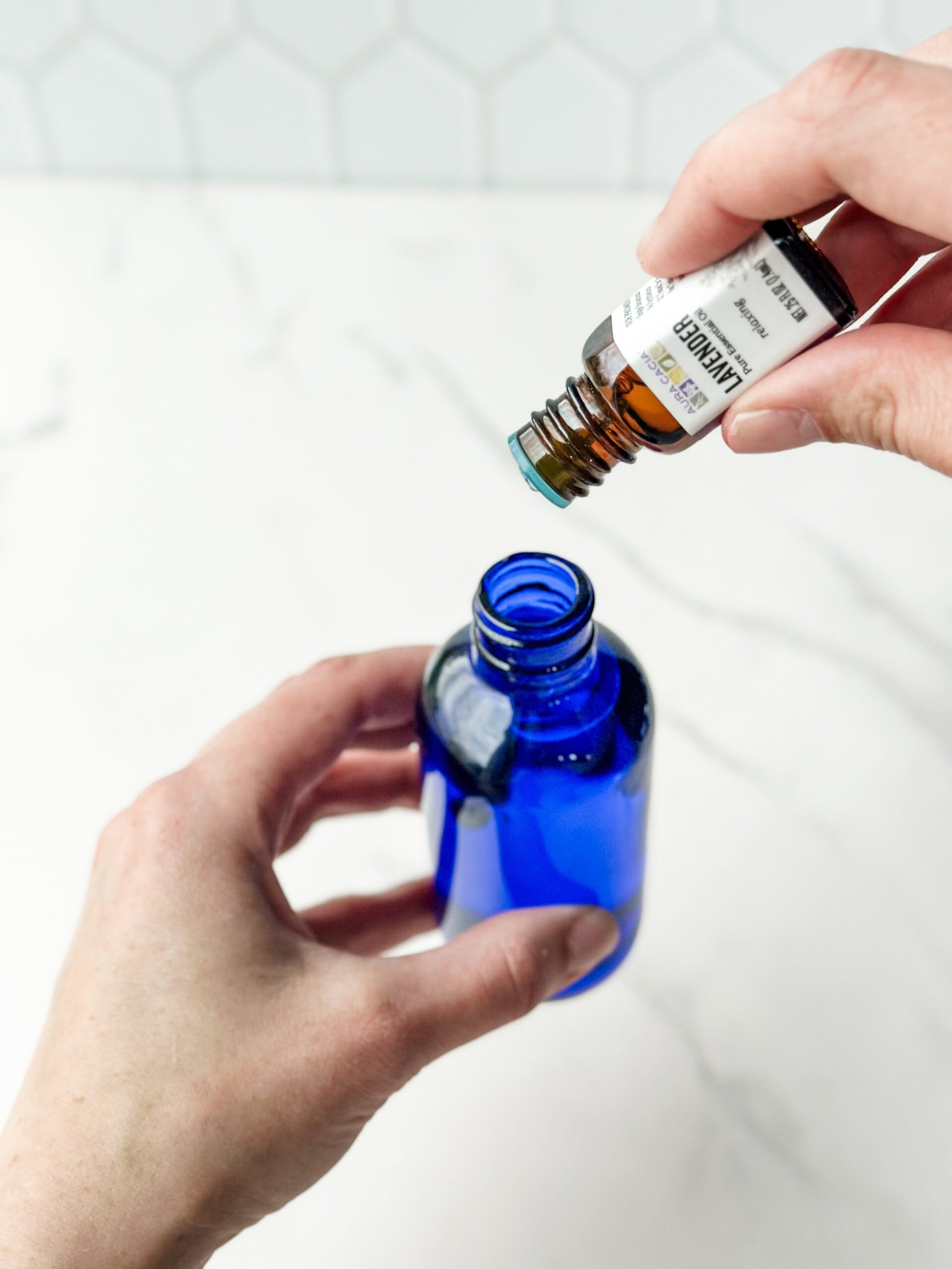 adding essential oils to blue glass bottle 