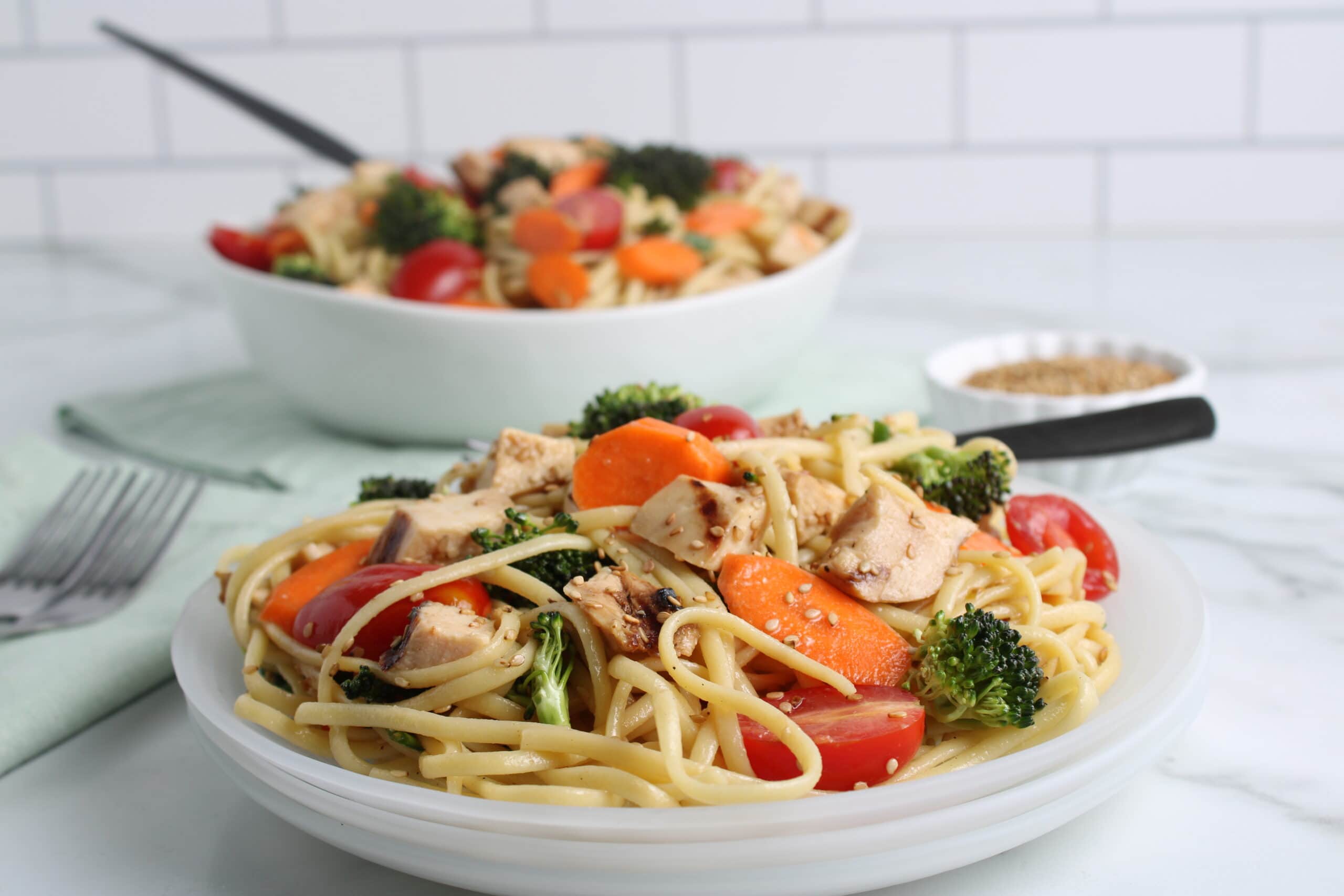 pasta salad plated on white plates with bowl in background