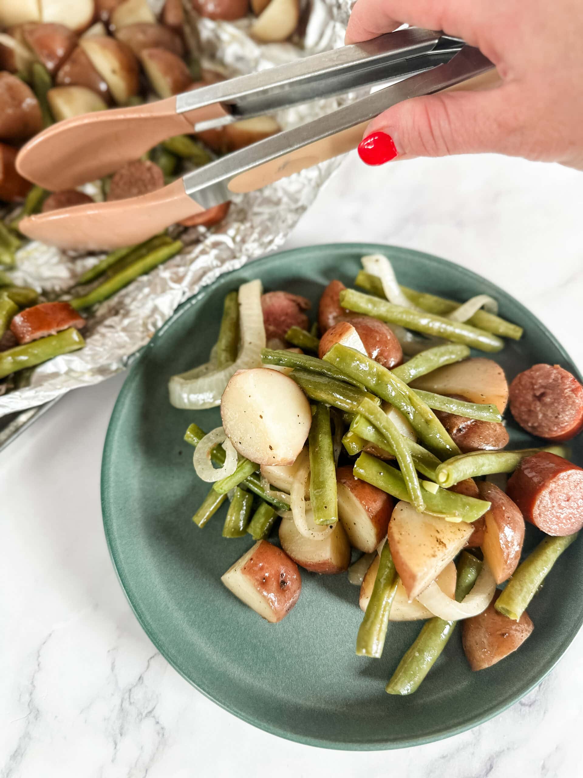 grilled sausage with green beans onions and potatoes on a plate