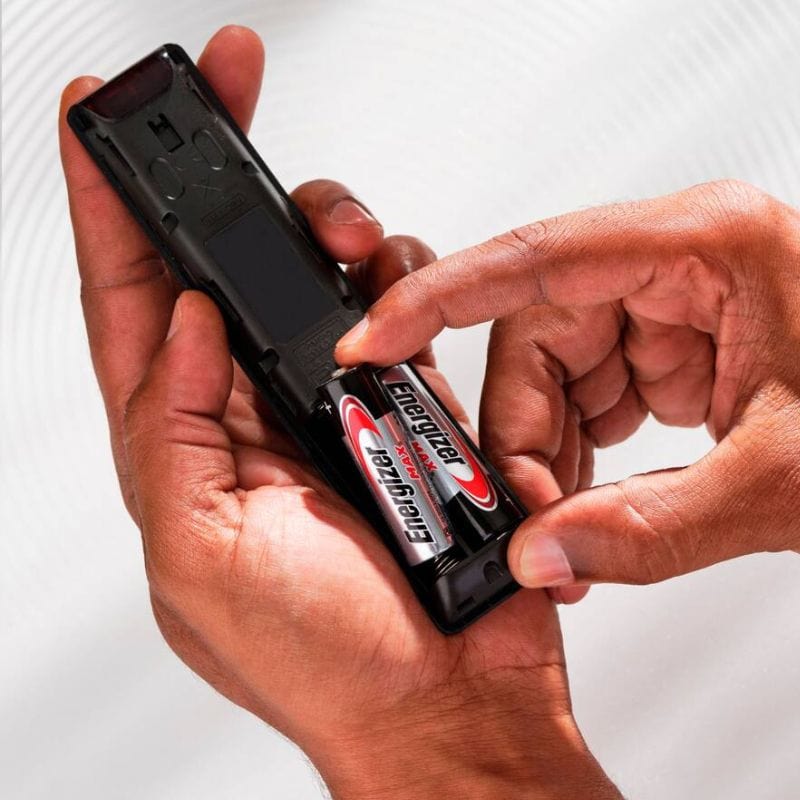 person putting batteries in remote
