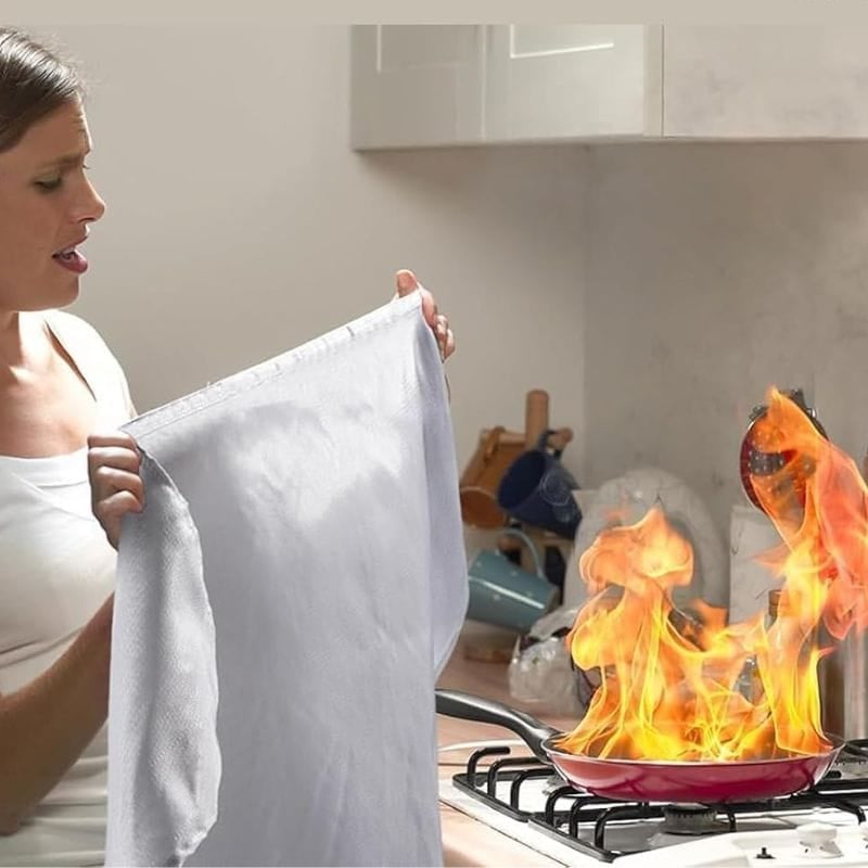 person using fire blanket on pan that is on fire