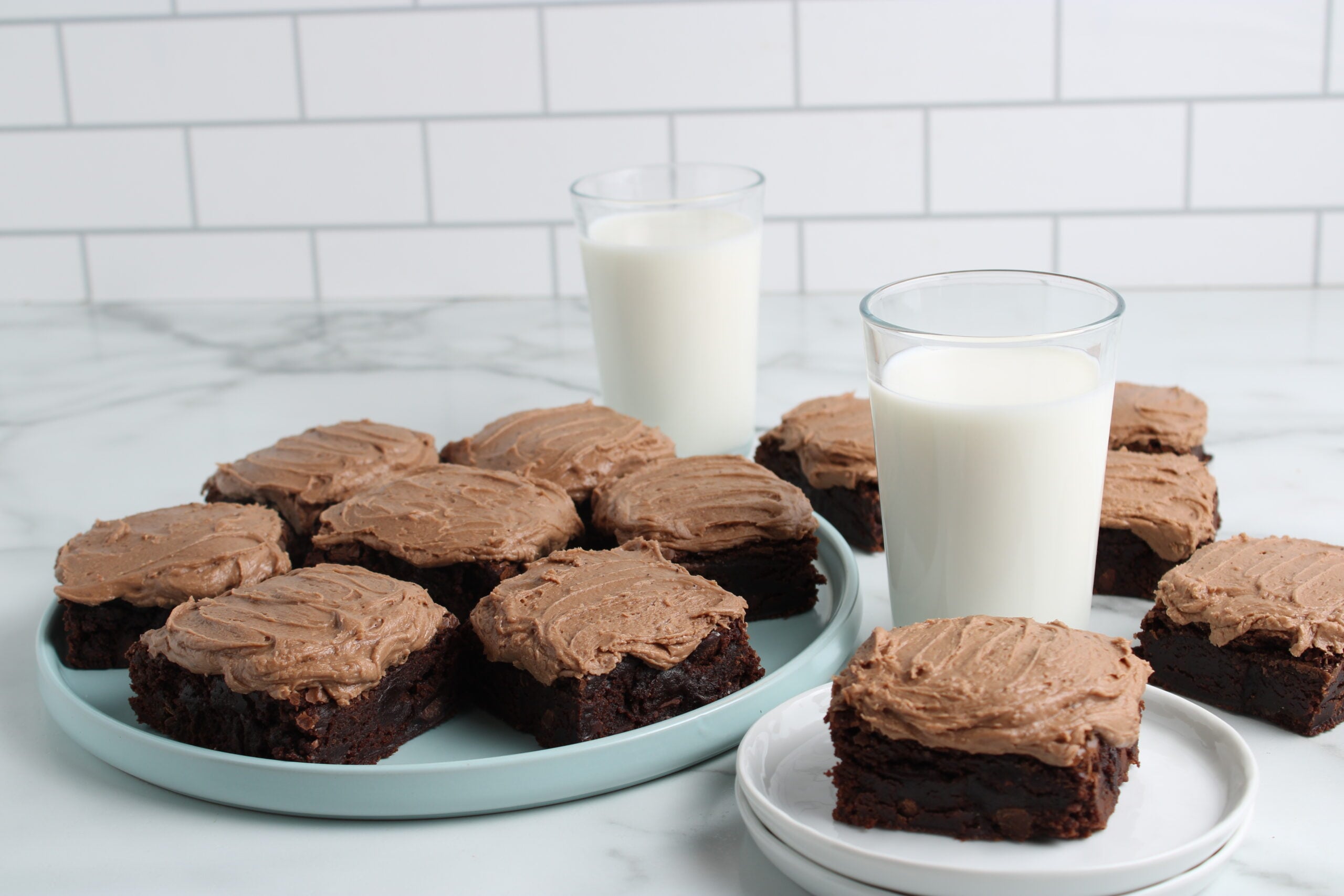 brownies with jiffy frosting on platters with milk