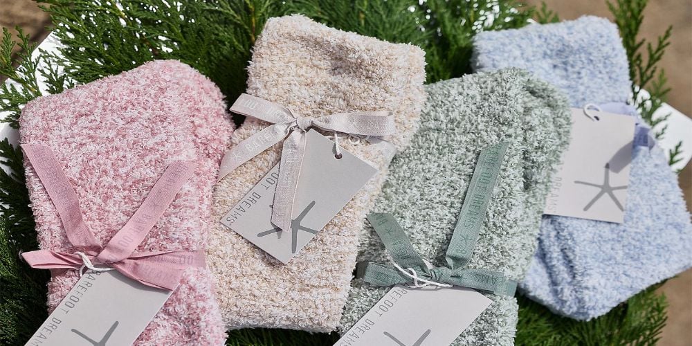 four pairs of barefoot dreams socks placed on garland