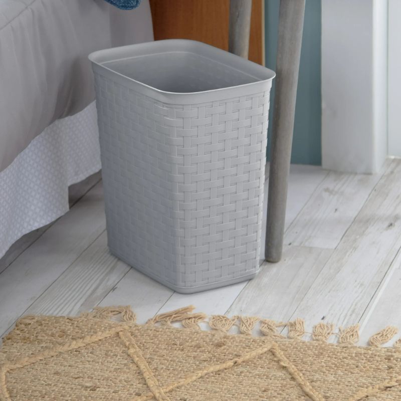 gray weaved garbage can next to bed