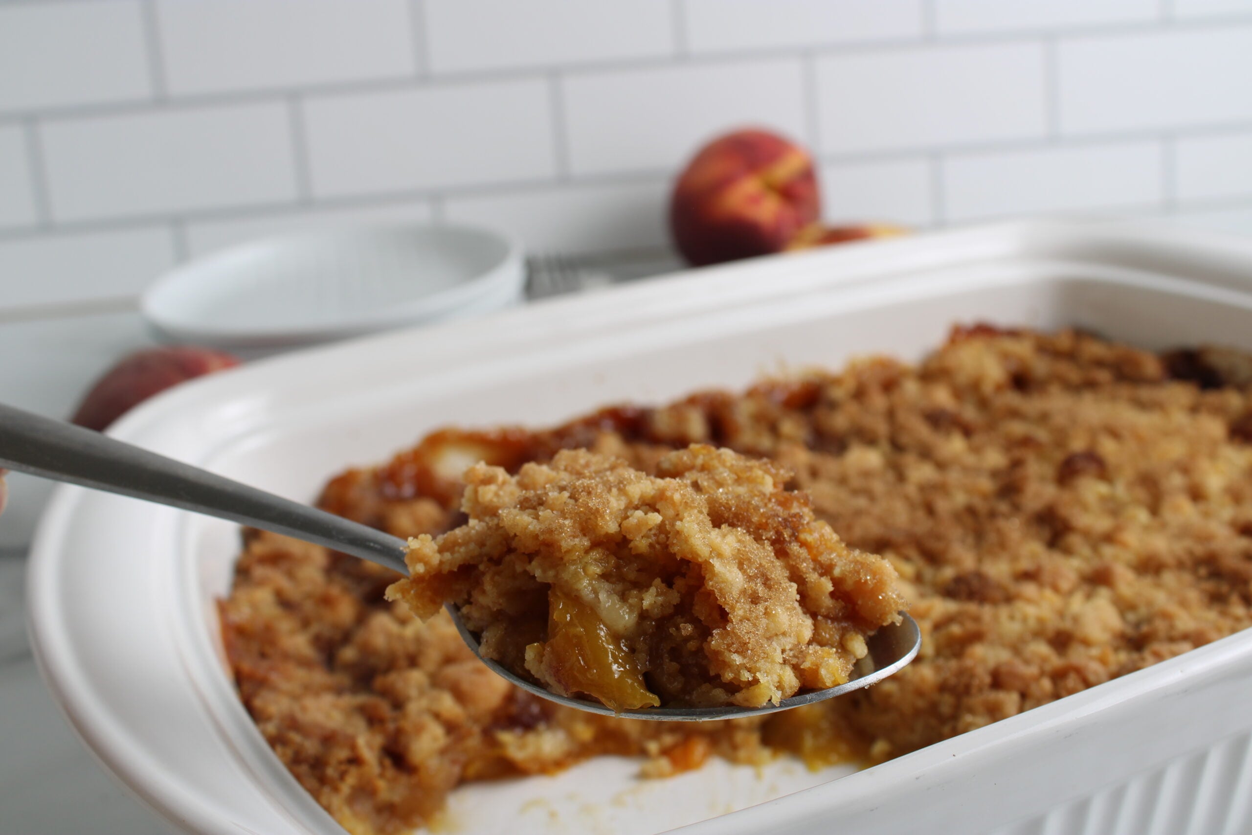 Cake Mix Peach Cobbler baked in cooking dish with bite on spoon
